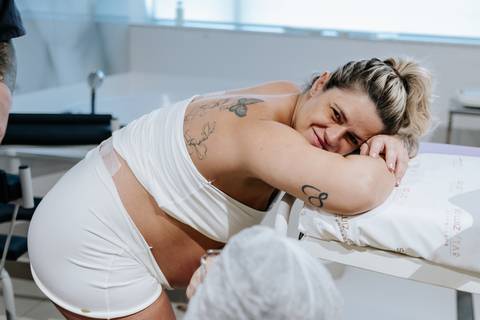Foto da gestante sorridente apoiada na maca hospitalar.'