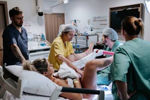 Foto da equipe médica auxiliando no nascimento da bebê.'