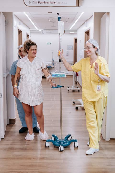 Foto da gestante caminhando pelo corredor com a equipe médica.'