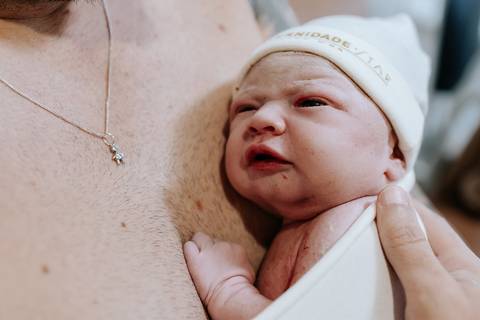 Foto em detalhe da bebê no colo do pai.'