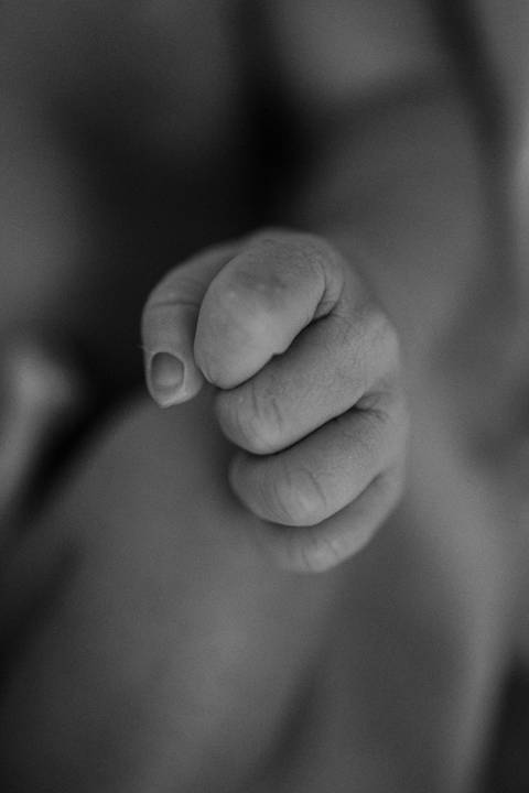 Foto em preto e branco do detalhe da mão da bebê.'