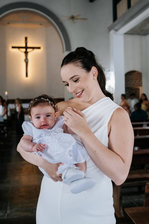 Foto da mãe segurando Olívia com carinho durante a cerimônia.'