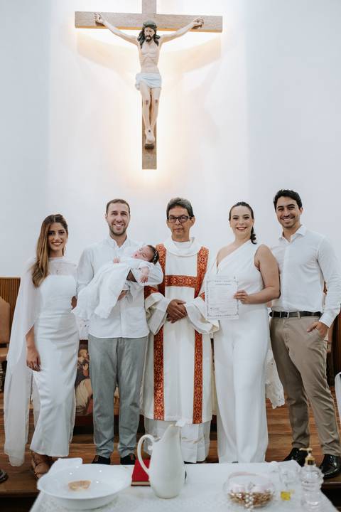 Foto oficial da família com o padre e o certificado de batismo.'