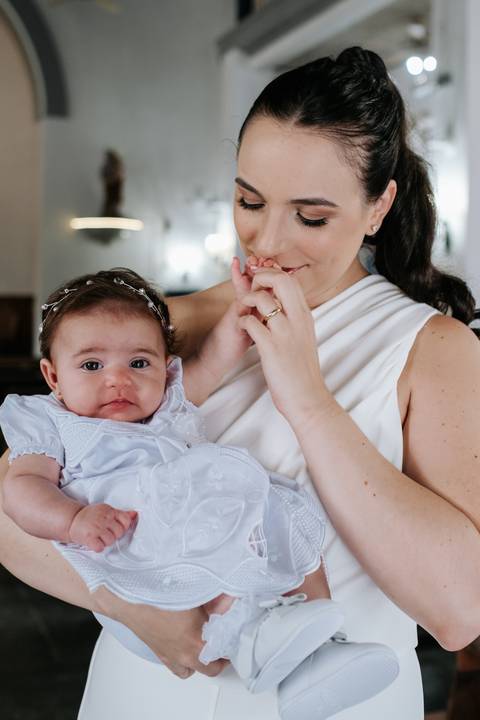 Foto da mãe beijando a mão da bebê Olívia.'