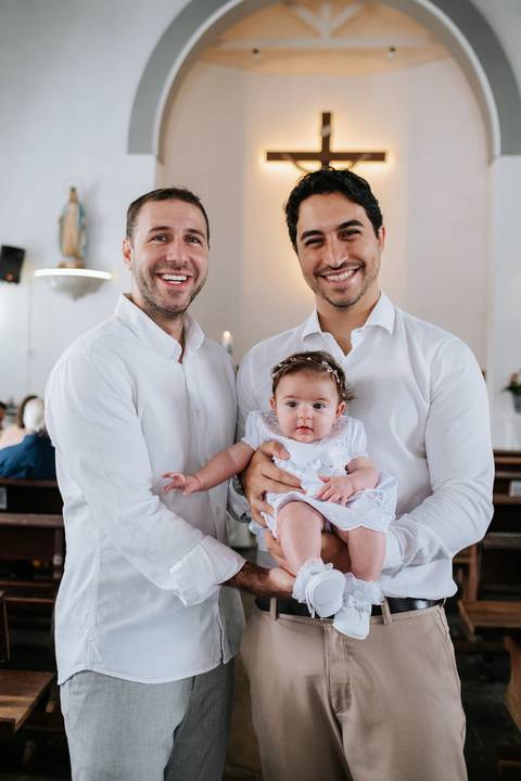 Foto do pai e padrinho com Olívia entre eles.'