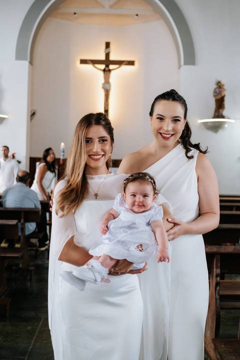 Foto da mãe e madrinha juntas com a bebê Olívia.'