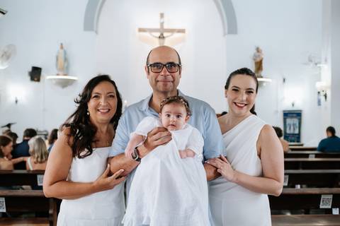 Foto da bebê Olívia com os avós e a mãe na igreja.'