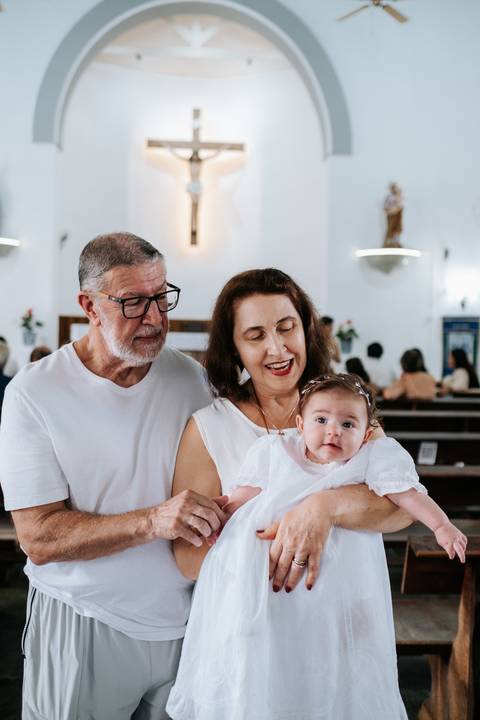 Foto aproximada da avó e avô sorrindo com a neta.'