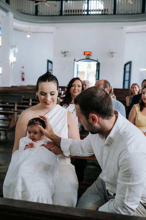 Foto do pai fazendo o sinal da cruz na testa da Olívia.'