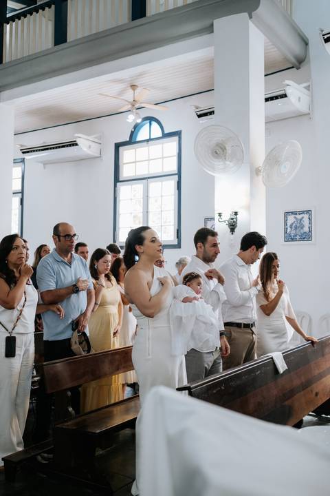Foto da família em pé acompanhando a leitura litúrgica.'