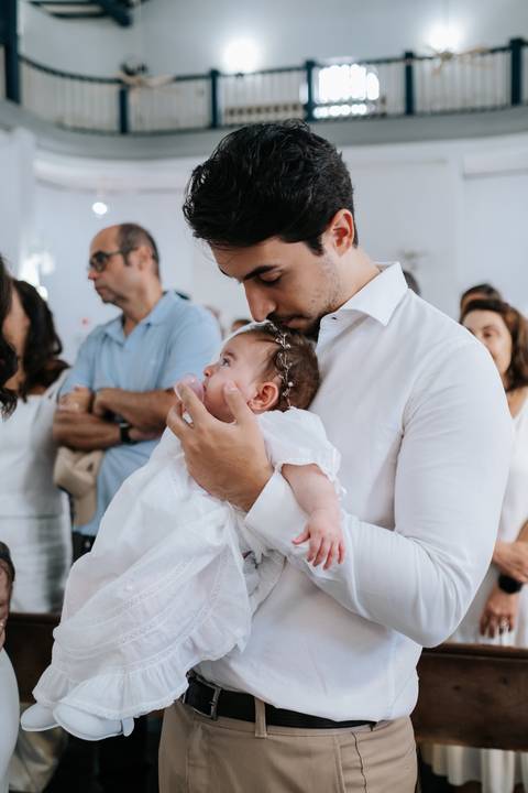Foto do padrinho beijando a cabeça da Olívia no colo.'