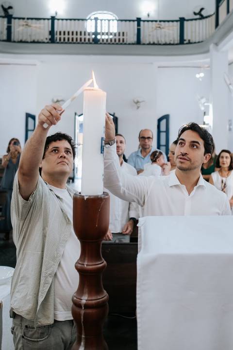 Foto do padrinho acendendo a vela no círio pascal.'