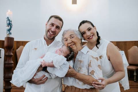 Foto dos pais e bisavó segurando a bebê Olívia.'