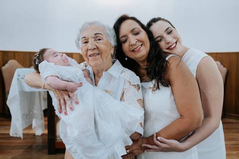 Foto de três gerações da família reunidas com a bebê.'