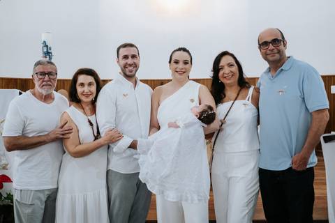 Foto dos pais e avós com a bebê na igreja. '