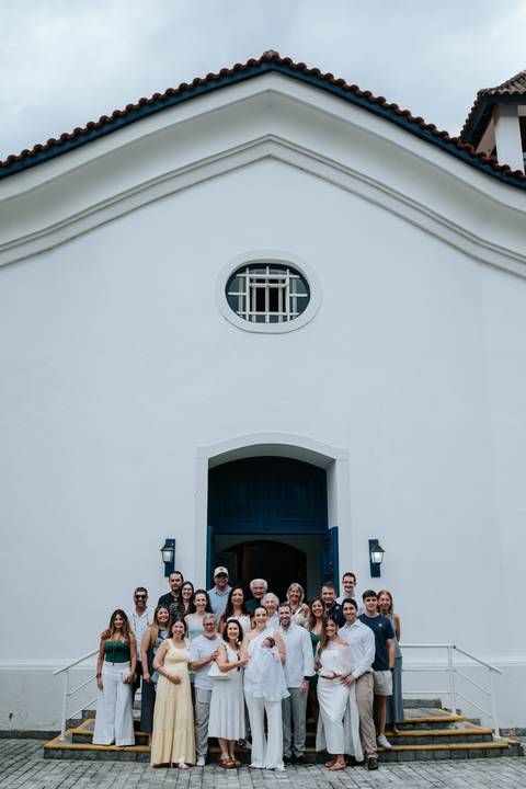 Foto da fachada da igreja branca com porta azul.'