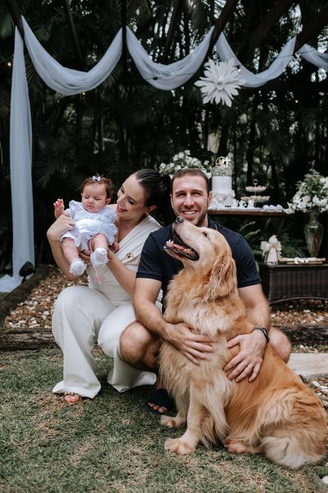 Foto da família sentada no jardim com seu cachorro de estimação.'