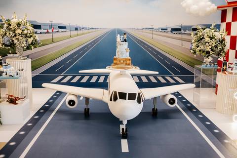 Foto da decoração da festa com pista de pouso e avião cenográfico.'