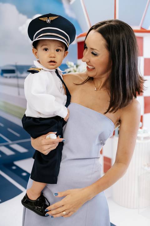 Foto da mãe segurando o aniversariante no colo.'
