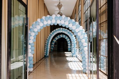 Foto do corredor da festa decorado com arcos de balões brancos e azuis.'