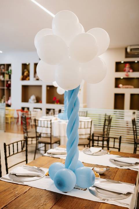 Foto aproximada de mesa decorada com bexigas imitando nuvens.'