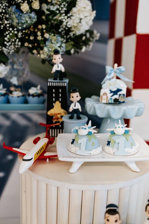 Foto em detalhe de bonecos de piloto e decorações na mesa do bolo.'
