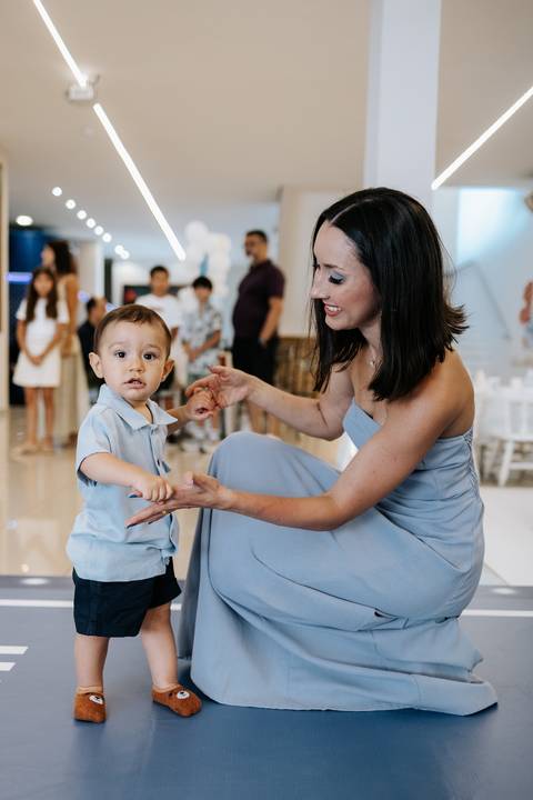 oto da mãe agachada brincando com o aniversariante na pista.'
