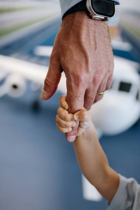 Foto em macro das mãos do pai segurando a mão do filho.'