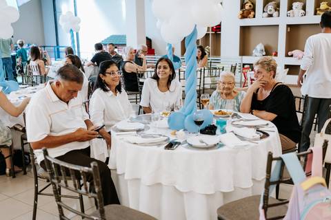 Foto da mesa de convidados decorada e preenchida com familiares.'