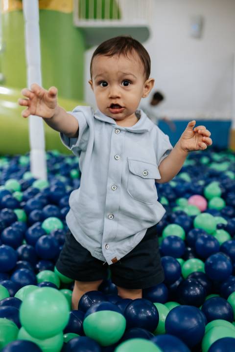 Foto aproximada do aniversariante de braços abertos nas bolinhas.'