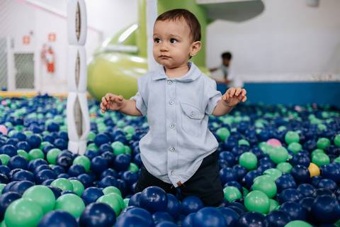 Foto do aniversariante de pé e equilibrado na piscina de bolinhas.'