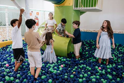 Foto panorâmica de crianças brincando nos brinquedos da festa. '