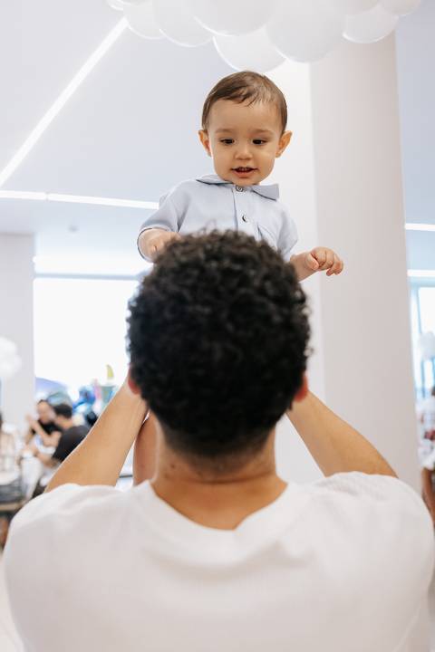 Foto em detalhe do convidado erguendo o aniversariante no colo.'
