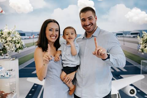 Foto aproximada dos pais posando com o filho no centro da pista.'