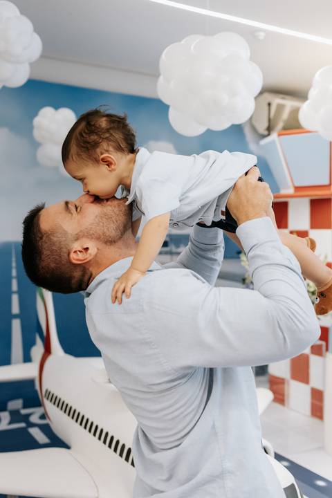 Foto do pai beijando o rosto do filho em momento de carinho.'