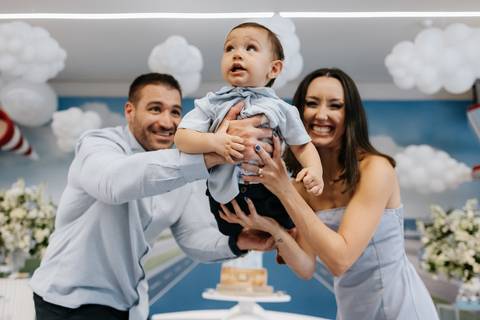 Foto de close dos pais brincando com o filho na mesa principal. '