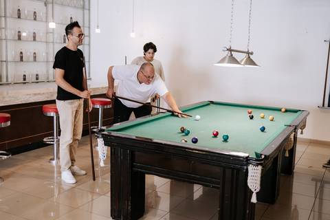 Foto de convidados jogando sinuca na área de lazer da festa.'