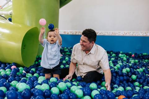 oto do aniversariante brincando na piscina de bolinhas com um adulto.'