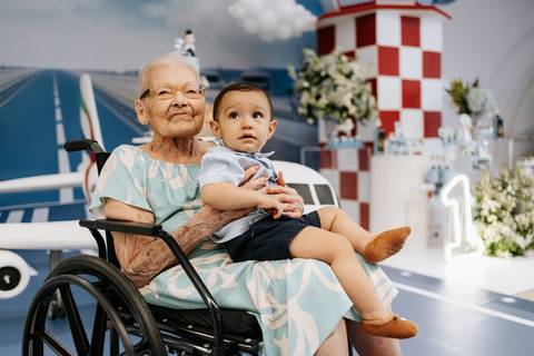 Foto da bisavó segurando o bisneto na pista de pouso.'