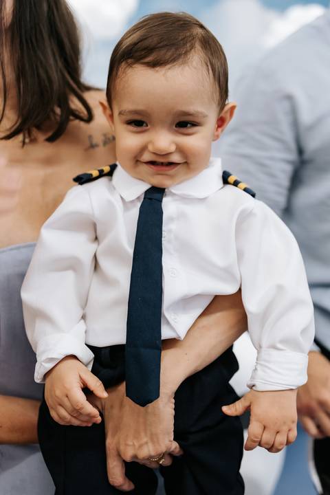 Foto em detalhe da gravata e divisas do uniforme de comandante.'