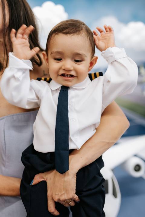 Foto de close do uniforme de piloto com as mãos do bebê para cima.'