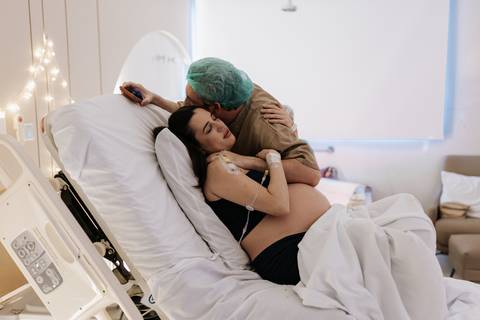 Foto do casal abraçado na maca durante o trabalho de parto.'
