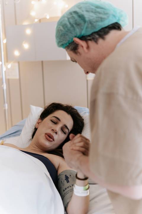 Foto aproximada da gestante em momento de concentração e dor recebendo apoio do marido. '