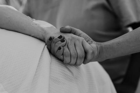Foto em preto e branco de mãos dadas em sinal de suporte.'