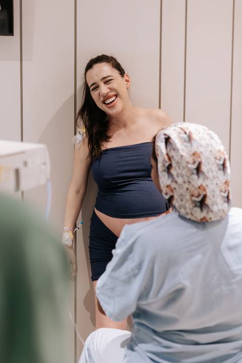 Foto da gestante em pé com apoio da equipe de enfermagem.'