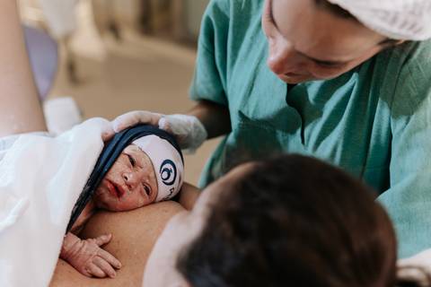 Foto do bebê Guilherme no colo da mãe logo após o nascimento.'