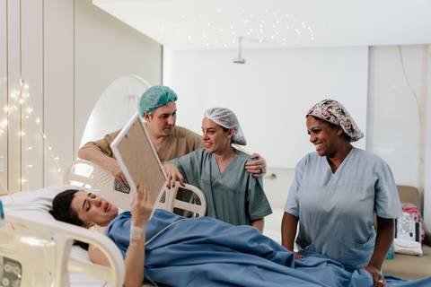 Foto da mãe na maca emocionada vendo o quadro da placenta. '