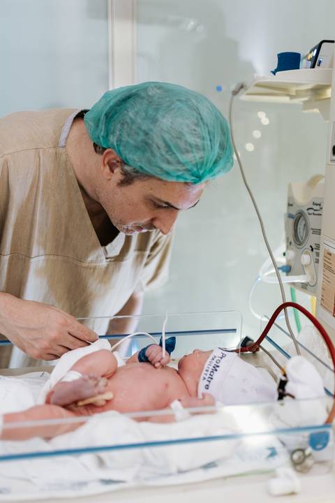 Foto do pai observando o filho no berço de acrílico.'