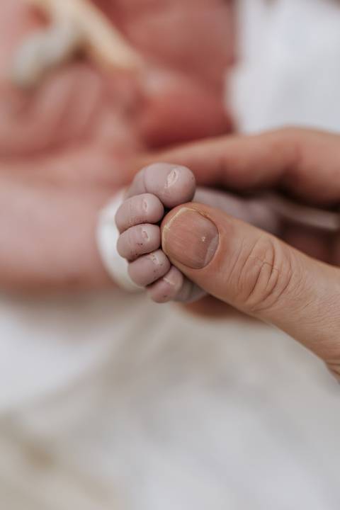 Foto em detalhe dos dedos do pé do recém-nascido com o dedo do pai. '