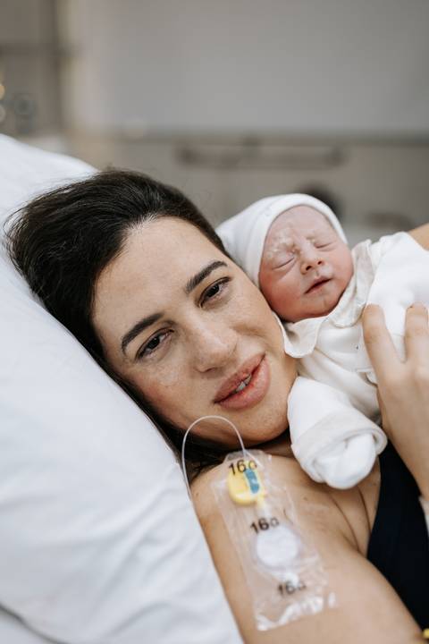 Foto da mãe com o rosto próximo ao bebê Guilherme, ambos deitados.'